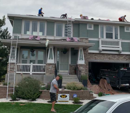 Roofers working on the roof of a two-story house.